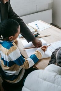 Educator helping children with schoolwork at a desk, promoting inclusive learning.